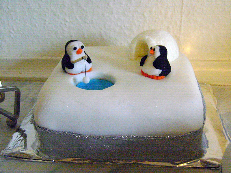 Two penguins fishing on a christmas cake