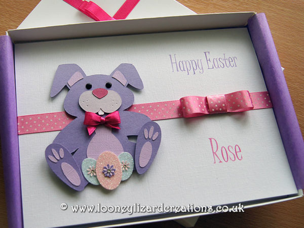Picture of a greeting card featuring a purple rabbit with decorated Easter eggs