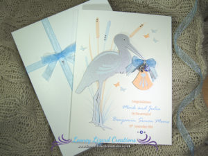 picture of a greeting card featuring a stork holding a blue baby bundle