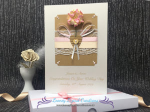 Card which features a pink flower, white lace, cabochon pearls and little wooden heart